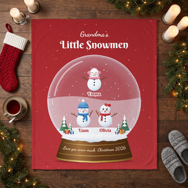 Snowman snow globe grandma blanket laid flat on a wooden floor with Christmas stocking and candles