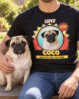 Adult cropped below the chin with a fawn pug on a backyard bench, wearing a black Coco pet hero shirt showing the same pug with a red cape.