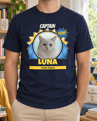 Navy comic book pet portrait tee with Luna the cat, CAPTAIN title, blue cape and Treat Patrol caption, photographed beside a colorful reading nook.