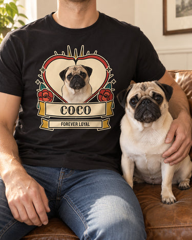 Adult cropped below the chin seated beside a fawn pug, wearing a black tattoo style dog shirt with the same pet portrait, red roses and Coco scroll.