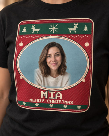 Close-up of cream pixel letters, tiny V stitches, Nordic reindeer and the oval portrait rim on a black Christmas face photo t-shirt